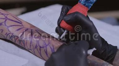 纹身大师在手臂上做纹身。 纹身机关闭。 艺术家在车间纹身。 概念：纹身师